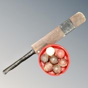 A vintage wooden cricket bat together with seven cricket balls