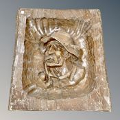A carved wooden panel depicting a man smoking a pipe
