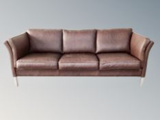 A Skalma three seater settee in brown leather on metal legs