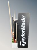 A group of snooker cues, hockey stick and a Taylor Made sign.