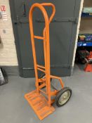 An orange spring loaded sack barrow (af).