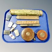 A tray of two vintage leather tape measures, spirit level, lighters,