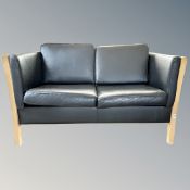 A Scandinavian wood framed black leather two seater settee