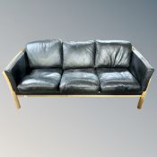 A Scandinavian wood framed black leather three seater settee