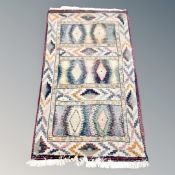 A fringed woolen rug of geometric design,