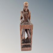 A tall carved wooden figure of a book keeper at desk holding quill pen, height 13.