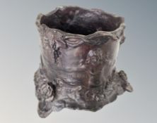 A patternated metal pot decorated with classical figures,