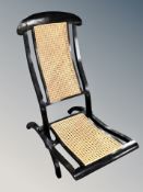 A painted folding wooden and cane steamer chair