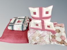 A box of assorted bed quilts and tapestry cushion