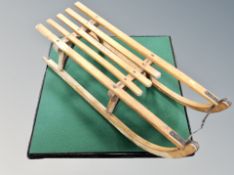 A folding baise topped card table and wooden sledge