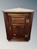 An oak hanging corner cabinet with panel door