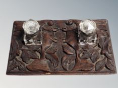 A 19th century carved oak desk stand with two glass inkwells