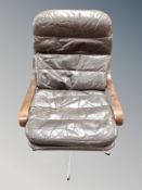 A Scandinavian brown leather beech and chrome swivel armchair