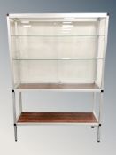 A glass and metal display cabinet with shelved interior and rosewood effect undershelf,