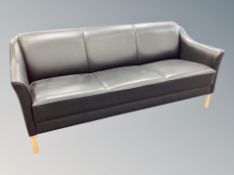 A Danish contemporary black leather four piece lounge suite comprising of three seater settee,