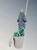 A metal twin handled dust bin with lid together with two garden parasols and hose pipe