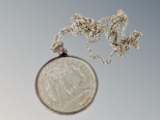 A silver dollar in mount on silver chain