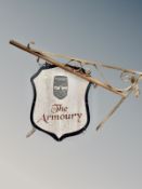 A double-sided sign on metal bracket 'The Armoury'