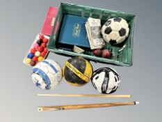 A box of four footballs, two bearing signatures, two piece billiard cue,