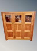 A contemporary stained pine triple door cabinet,