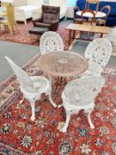 A cast metal circular garden table and four painted metal chairs