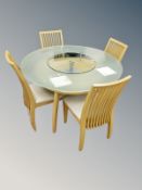 A contemporary oak effect and frosted glass circular dining table and four chairs