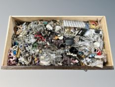 A wooden drawer containing a large quantity of costume jewellery