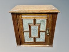 An Edwardian oak wall cabinet with mirrored door,