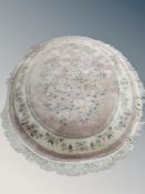 A Chinese fringed oval rug on pink ground,