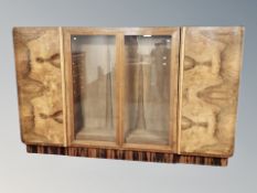 An Art Deco style figured walnut and rosewood veneered cabinet with shelved interior,