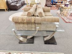 A contemporary glass coffee table with decorative shaped supports,