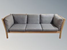 A late 20th century beech framed three seater settee with dark grey cushions,