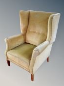 An early 20th century wing backed armchair in olive dralon