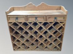 A stained pine wine rack fitted with three drawers,