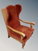 A 20th century oak wing backed armchair in studded dralon