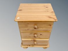 A contemporary pine three drawer bedside chest,