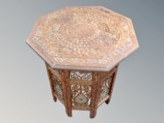 An Indian octagonal heavily carved occasional table on folding stand,