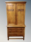 An early 20th century carved oak double door cabinet on stand with three drawers,