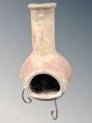 A terracotta chiminea on wrought metal stand,