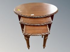 A reproduction mahogany oval nest of three tables,