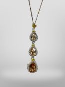 A silver drop pendant set with amber coloured crystals on silver chain