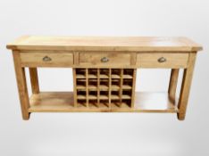 A contemporary solid oak dresser base fitted three drawers and wine rack,