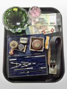 A precision drawing set, belt, clock winding key, Scottish glass paperweight, Peruvian bank notes,