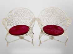 A set of four wrought metal garden armchairs with drop in seats and a matching table