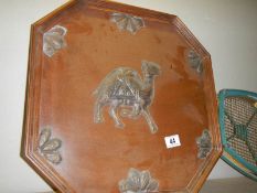 A wooden wall plaque featuring a camel.