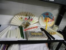 An oriental fabric covered box, 2 fans and a quantity of candles.