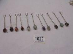 Eleven cocktail forks with semi precious stone tops.