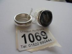 An oval heavy silver ring with a blue stone and a silver band or wedding ring,