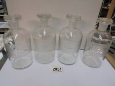 A set of four glass chemists bottles with stoppers (some bruising to stoppers).