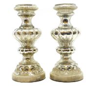 A pair of silvered glass candle stands,